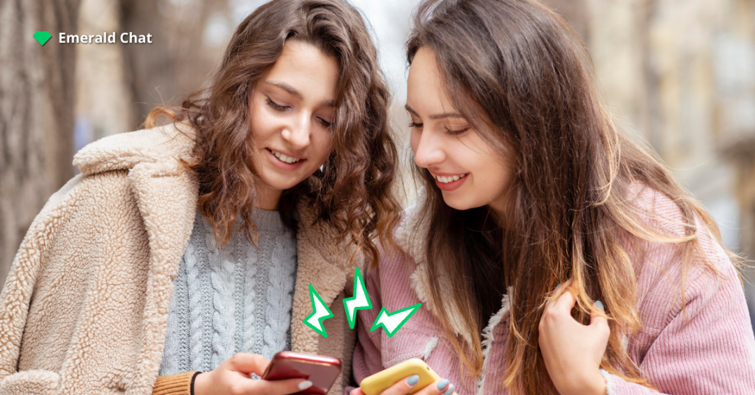 Two friends smiling while chatting on their phones outdoors, symbolizing online connections and modern chat rooms. Emerald Chat branding in the corner.
